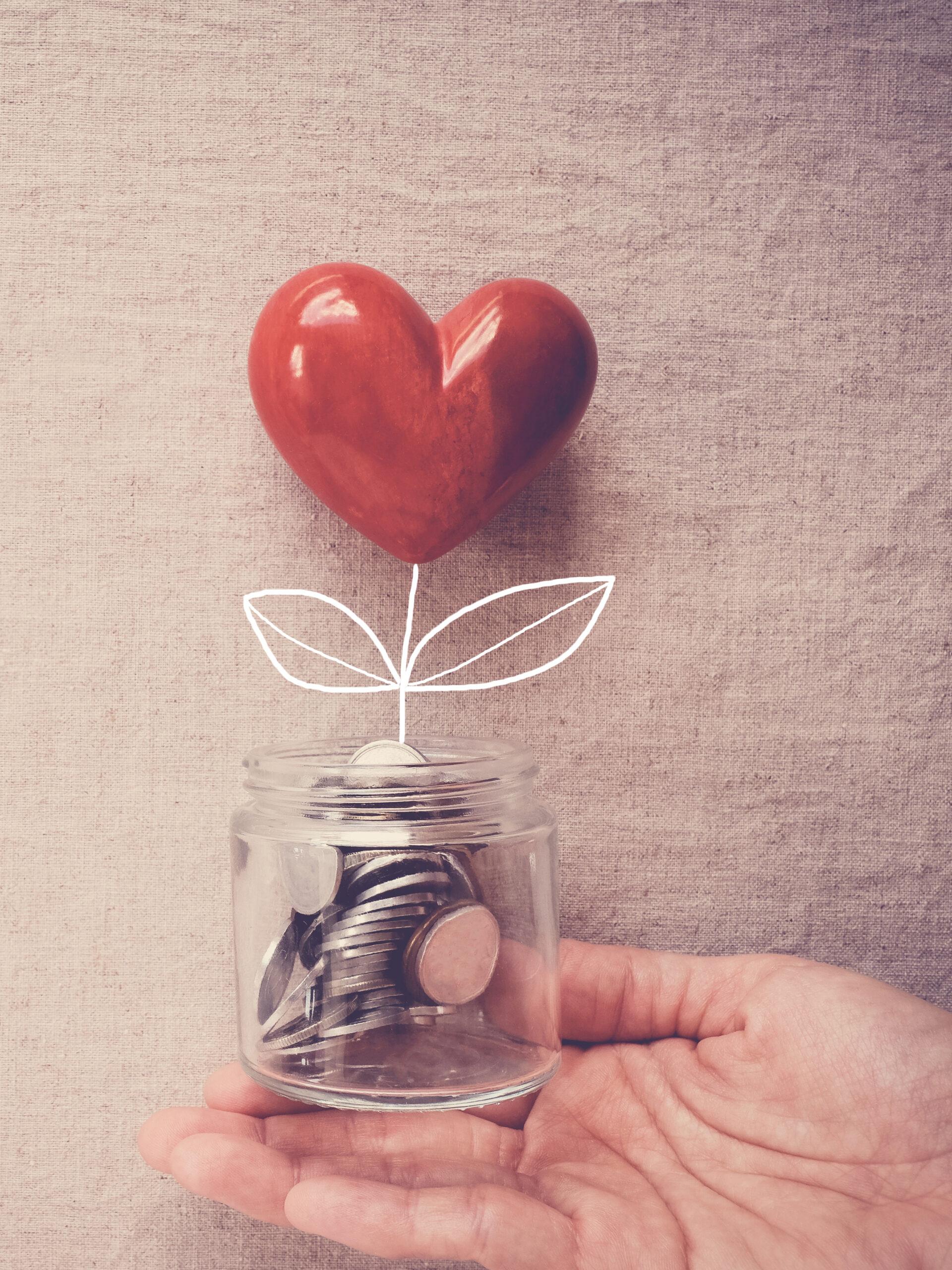 Hand holding a jar of heart tree growing on money coins, social